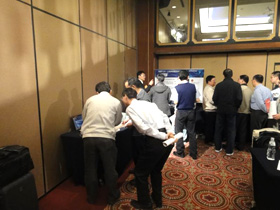 Participants gathered in front of display tables, asking questions 